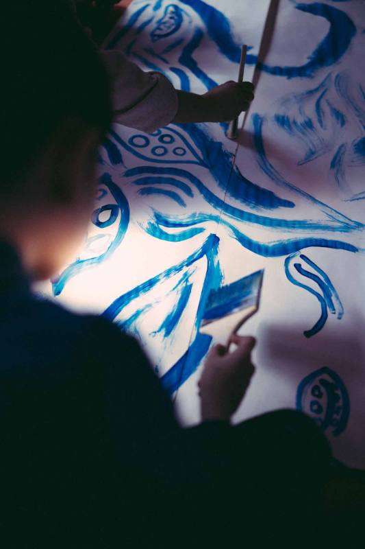 Une jeune fille peint un signe au pinceau sur la toile blanche.